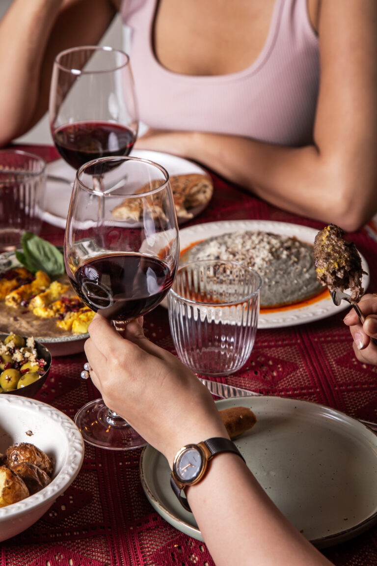 Copa de vino tinto en primer plano con ambiente cálido y elegante de Pérsico, restaurante persa en Madrid