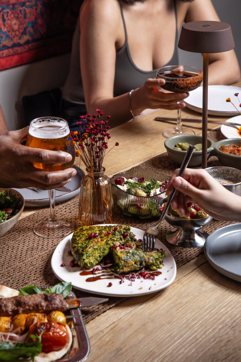 Mesa con lámpara de diseño, copa de vino y alfombra persa de fondo, ambiente cálido de Pérsico, restaurante persa en Madrid